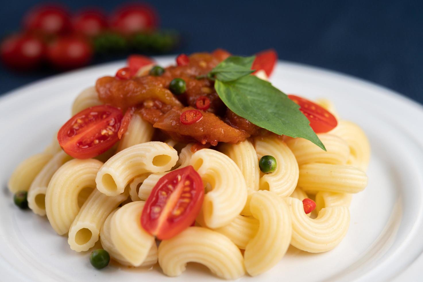 Gebratene Makkaroni mit Tomaten, Chili, Pfeffersamen und Basilikum foto