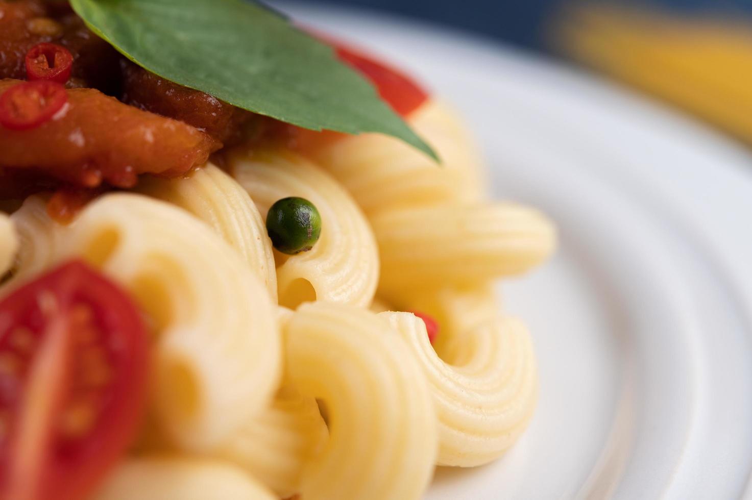 Gebratene Makkaroni mit Tomaten, Chili, Pfeffersamen und Basilikum foto