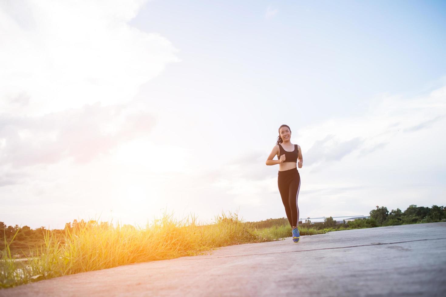 eine junge glückliche Läuferin, die draußen joggt foto