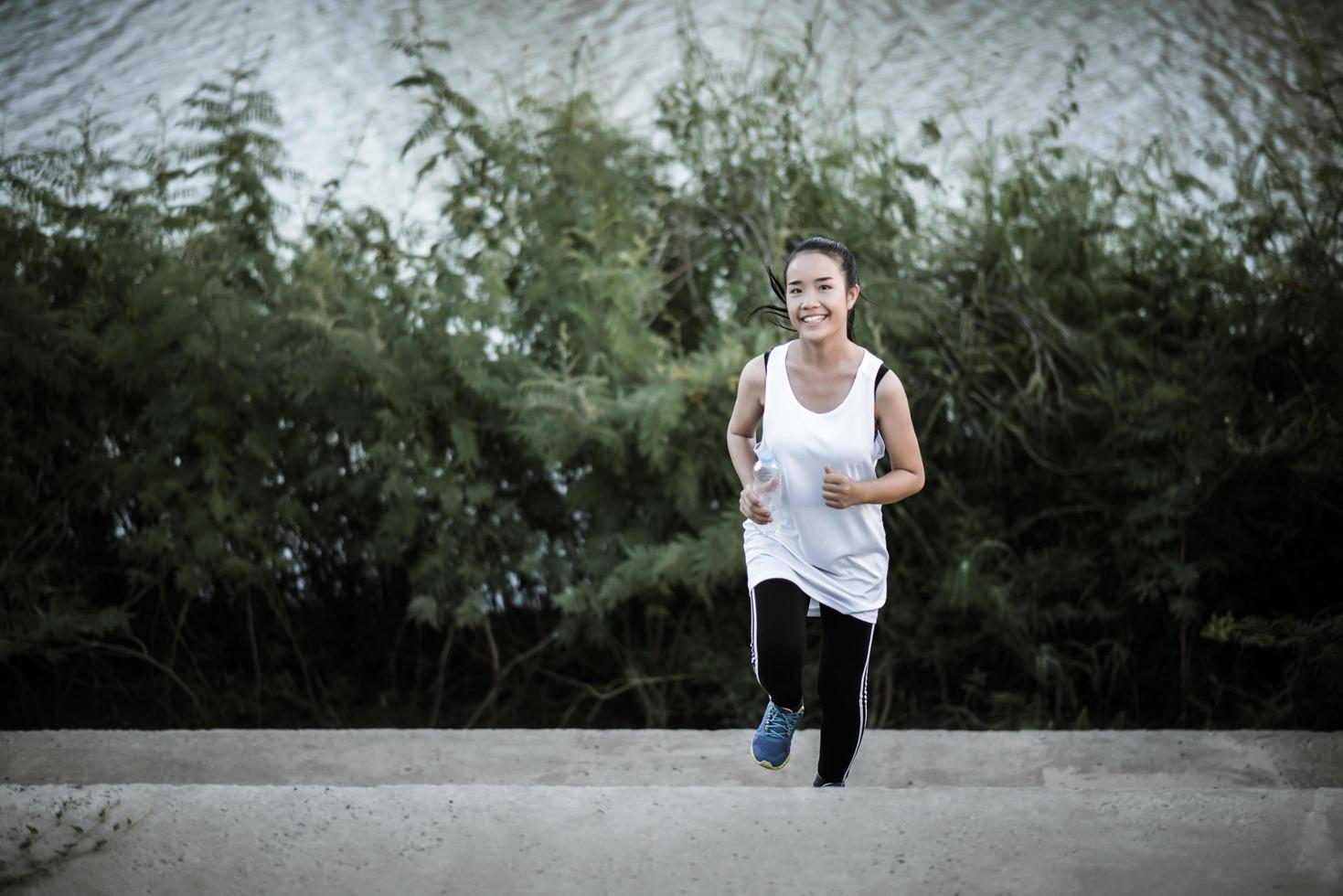 eine junge glückliche Läuferin, die draußen joggt foto