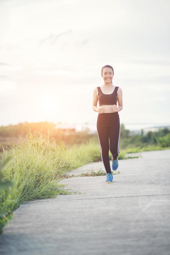 eine junge glückliche Läuferin, die draußen joggt foto