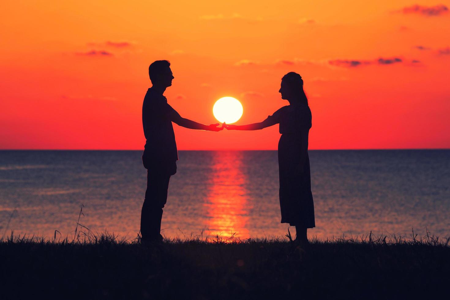 zwei Leute, die Hände bei Sonnenuntergang halten foto