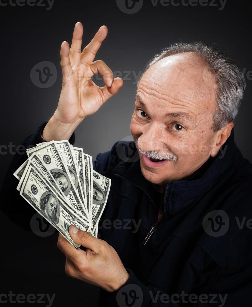 älterer herr, der einen stapel geld hält foto