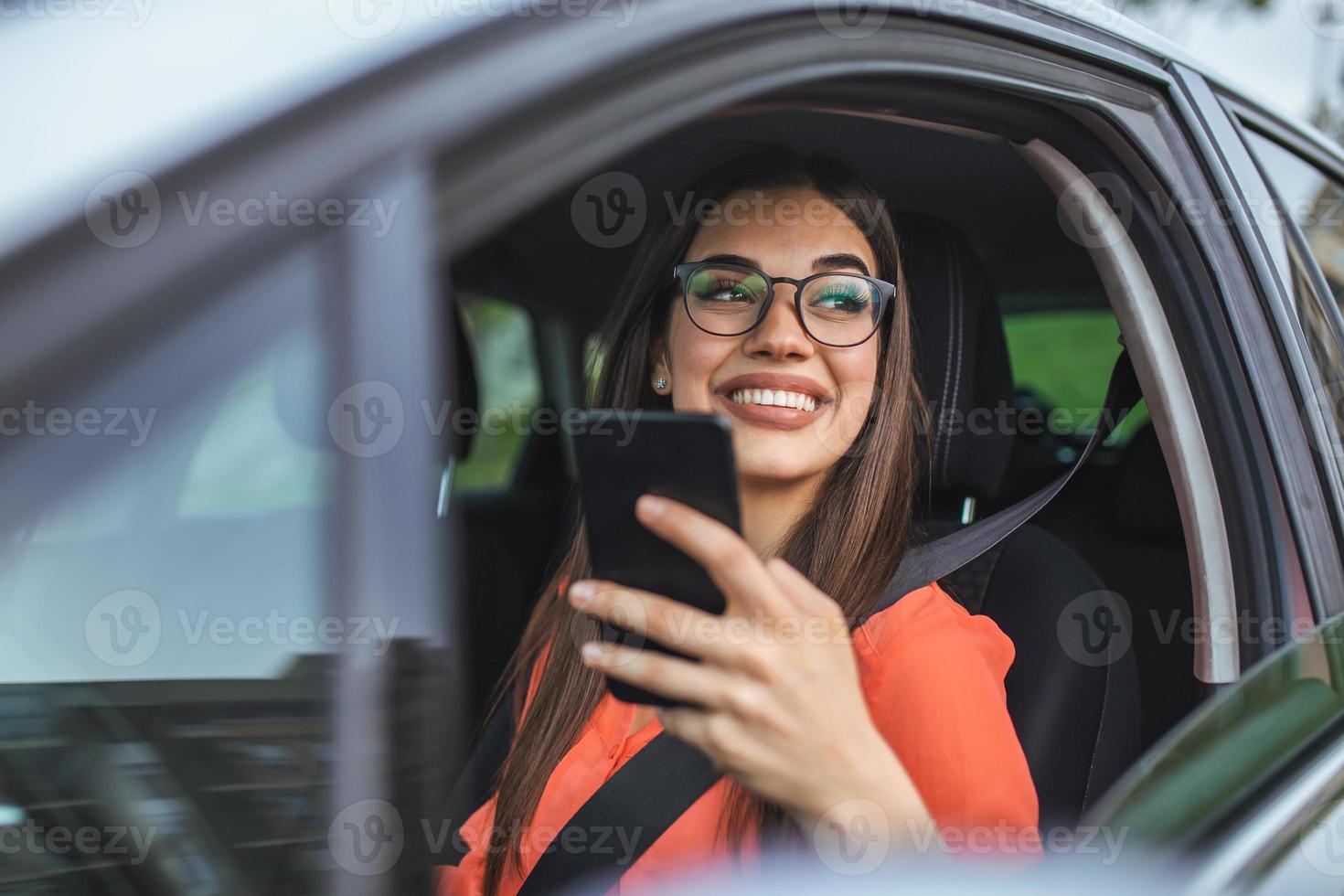 Fahrerin mit einem Smartphone im Auto. Fahrerin mit einem Smartphone im Auto. freizeit-, roadtrip-, technologie-, reise- und personenkonzept - glückliche frau, die auto mit smartphone fährt foto