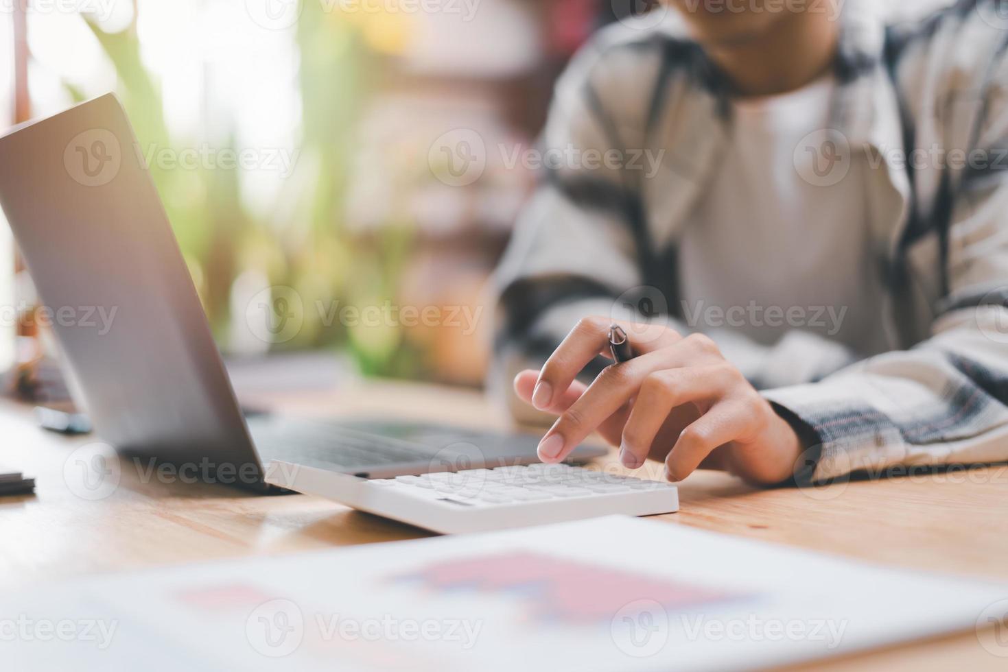 geschäftsmann, der zahlen in unternehmensfinanzdokumenten mit einem taschenrechner berechnet, analyse von unternehmensfinanzdaten, planung zur bewertung und überprüfung von budgets, konzept von finanzen und investitionen foto