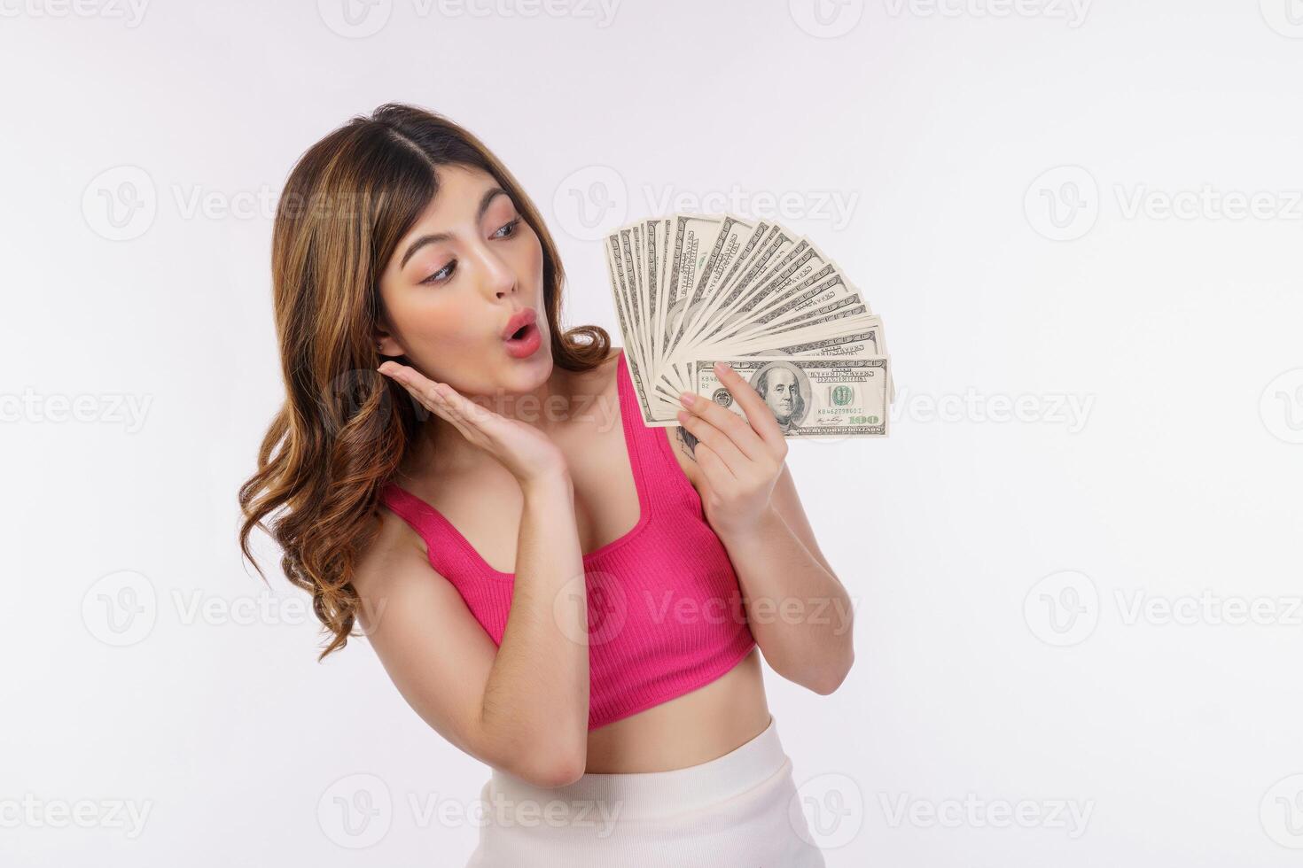 Porträt einer aufgeregten jungen Frau, die einen Haufen Dollar-Banknoten hält, die über weißem Hintergrund isoliert sind foto