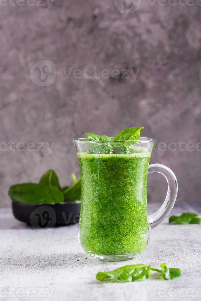 frischer spinat-smoothie in einem glas und einer schüssel mit blättern. natürliches Antioxidans. vertikale Ansicht foto