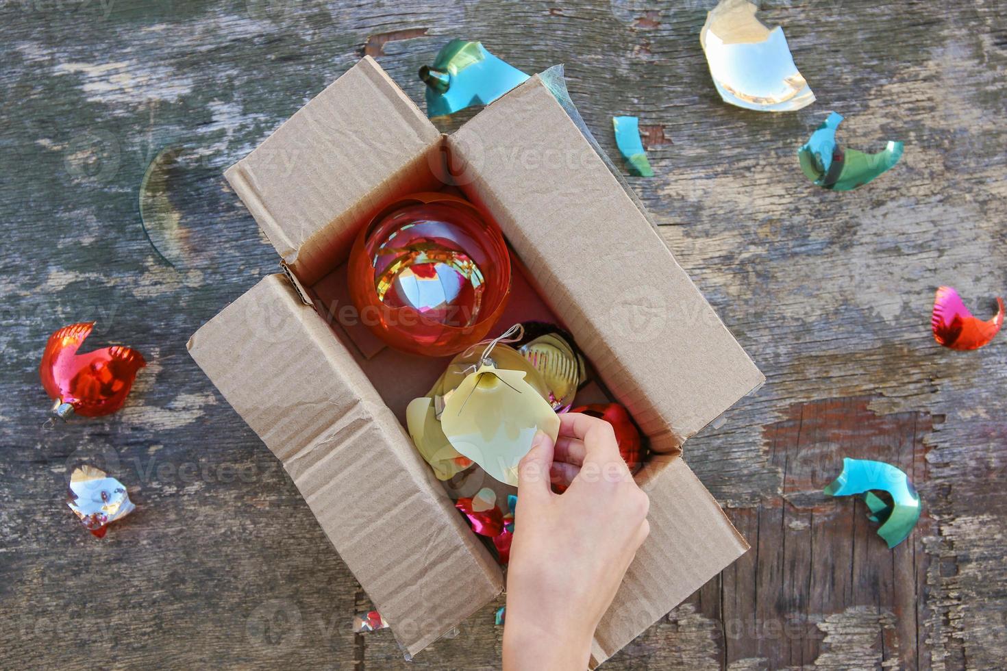eine frau erhielt ein paket mit zerbrochenen weihnachtsbaumglaskugeln. das Konzept einer schlechten Warenverpackung. foto