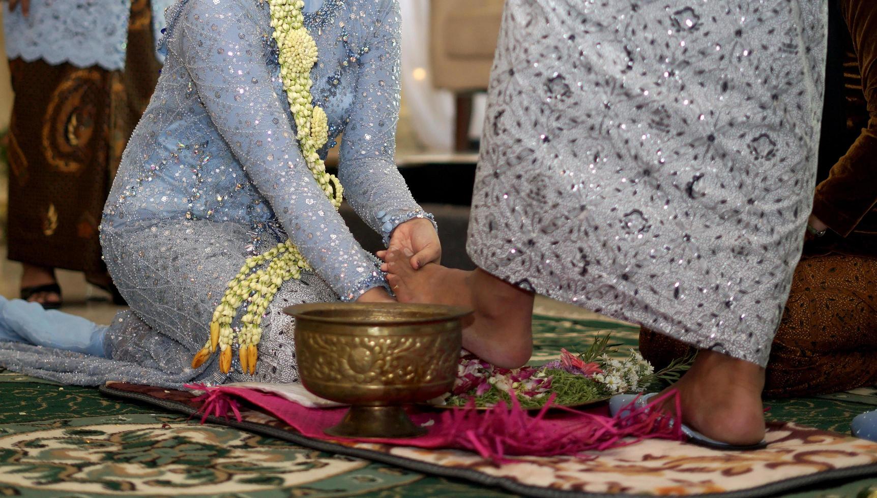 braut wäscht dem bräutigam die füße in der traditionellen hochzeitszeremonie in indonesien foto
