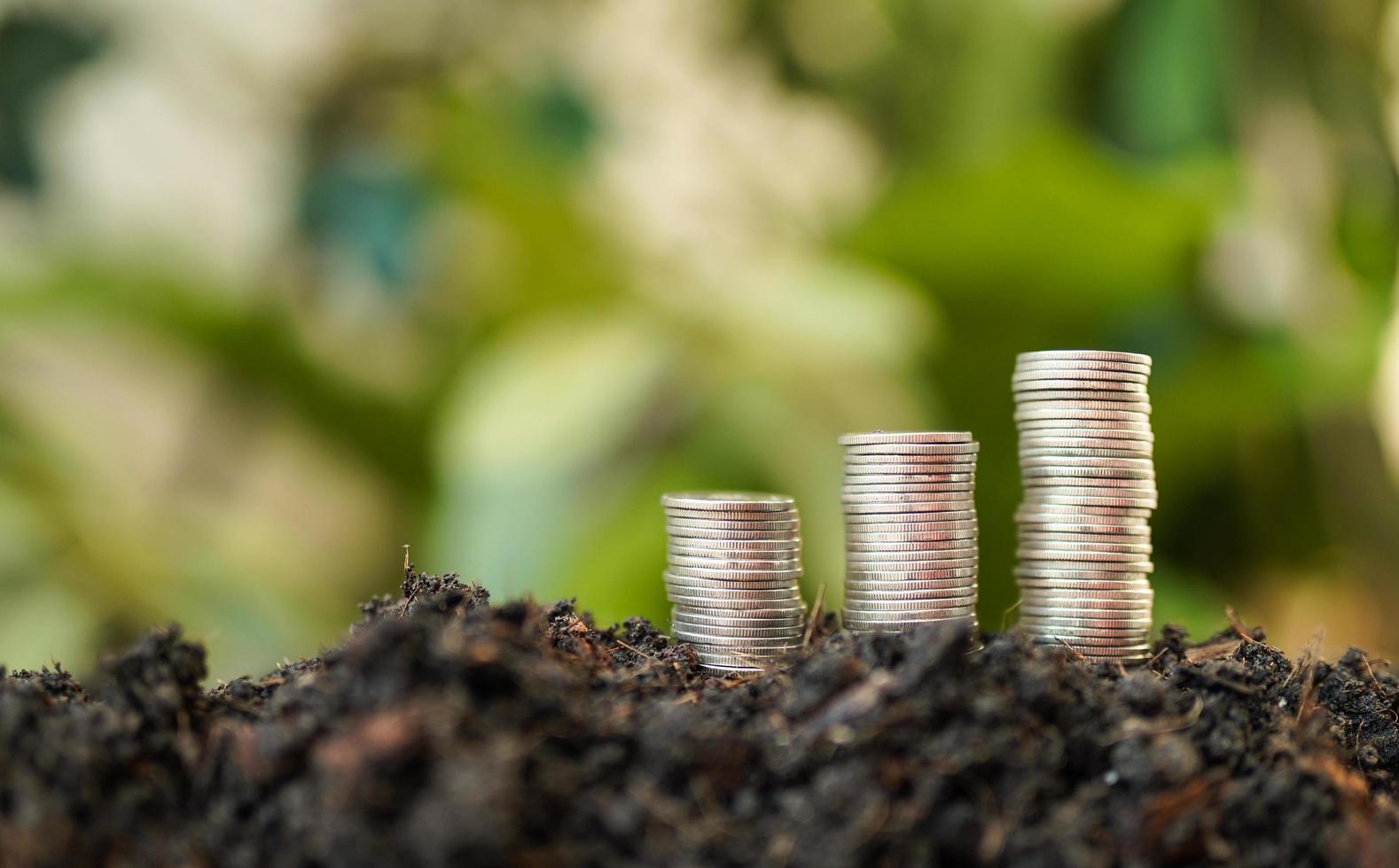 Haufen Silbermünzen mit grünem Naturhintergrund. geldspar- und geschäftsfinanzierungskonzept, geschäftswachstum und geldzukunft, finanzieller erfolg foto