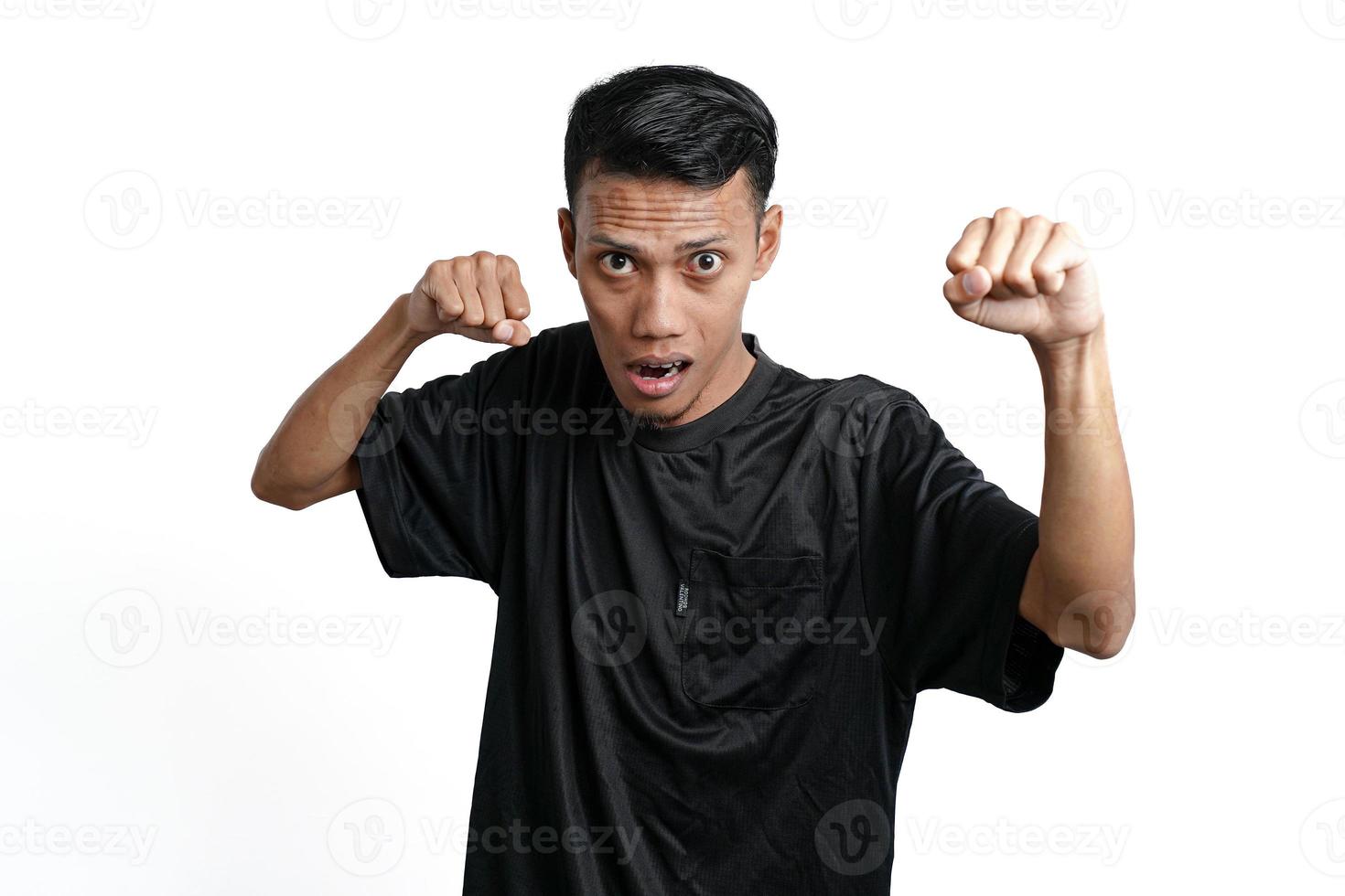 asiatischer mann, der schwarzes trainingst-shirt trägt und gestikuliert, um zu kämpfen. durch weißen Hintergrund isoliert foto