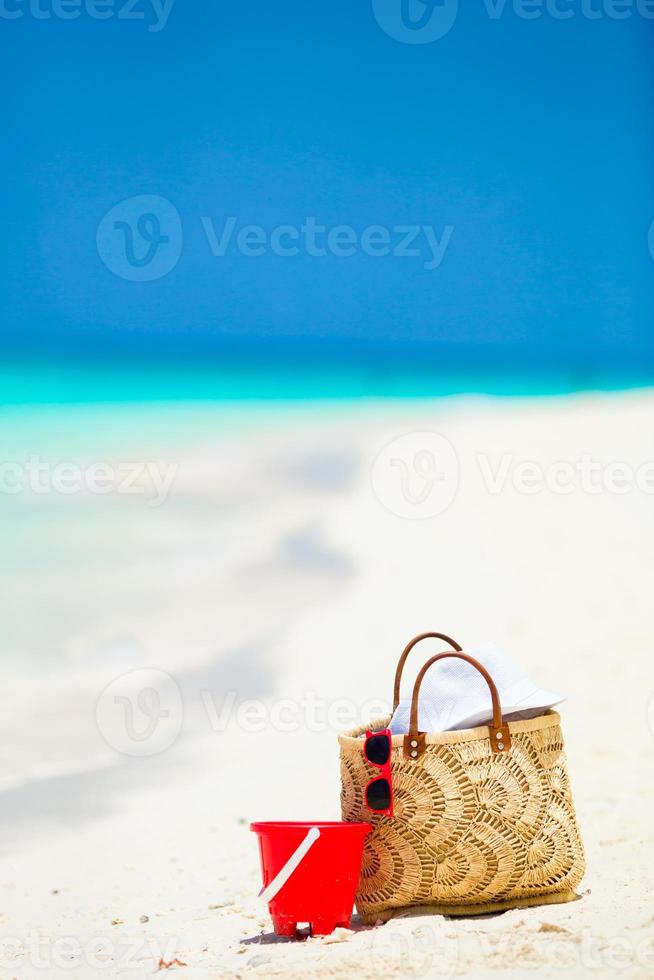 Strandzubehör - Strohsack, weißer Hut und rote Sonnenbrille am Strand foto
