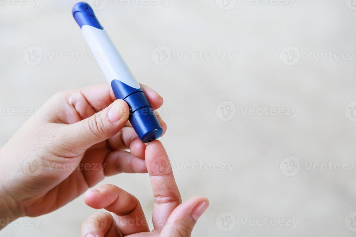 Nahaufnahme von Frauenhänden mit einer Lanzette am Finger, um den Blutzuckerspiegel mit einem Glukosemessgerät zu überprüfen, das als Medizin, Diabetes, Glykämie, Gesundheitsversorgung und Personenkonzept verwendet wird. foto