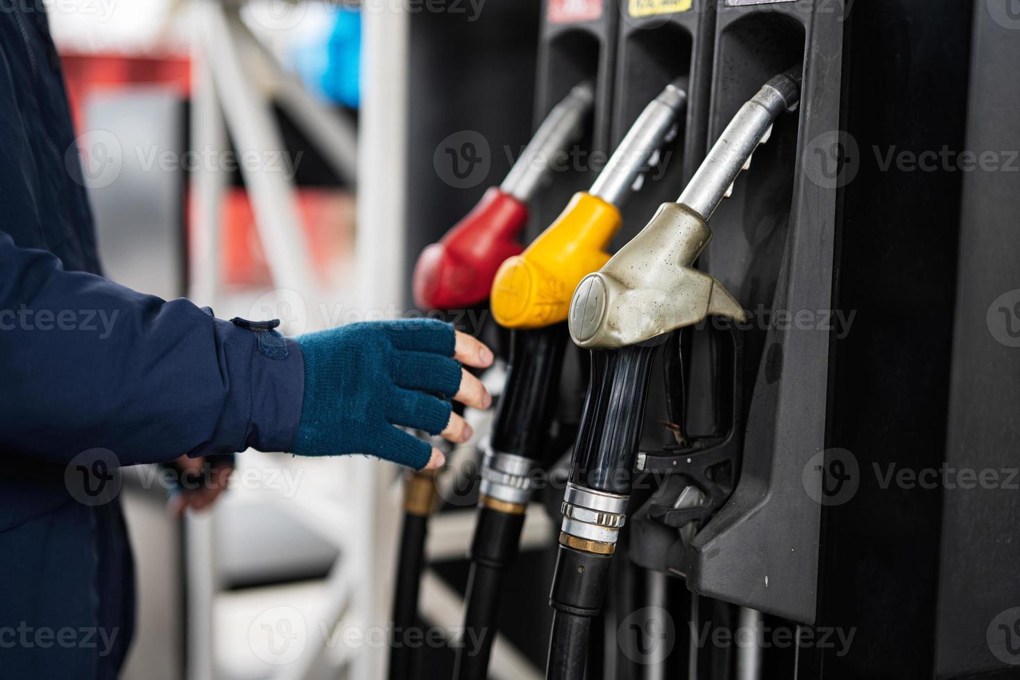 Nahaufnahme der Hand des Mannes, die die Kraftstoffpumpe hält, während er bei kaltem Wetter sein Auto an der Tankstelle betankt. foto