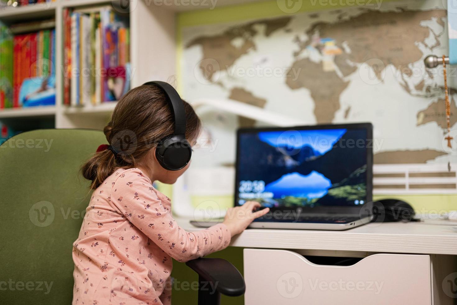 glückliches mädchen, das kopfhörer mit laptop trägt, um von zu hause aus zu lernen, genießt ihre fernausbildung, hat online-unterricht mit schullehrer. foto