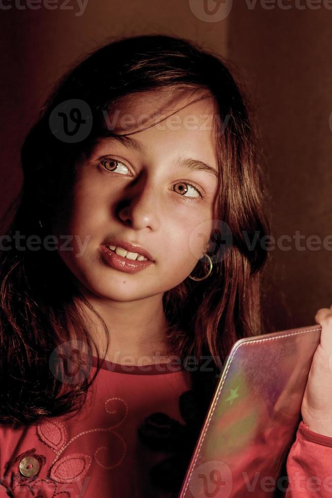 Ein junges Mädchen unter der Beleuchtung einer Tischlampe mit einem Notizbuch in ihren Händen. träumte das Mädchen. foto