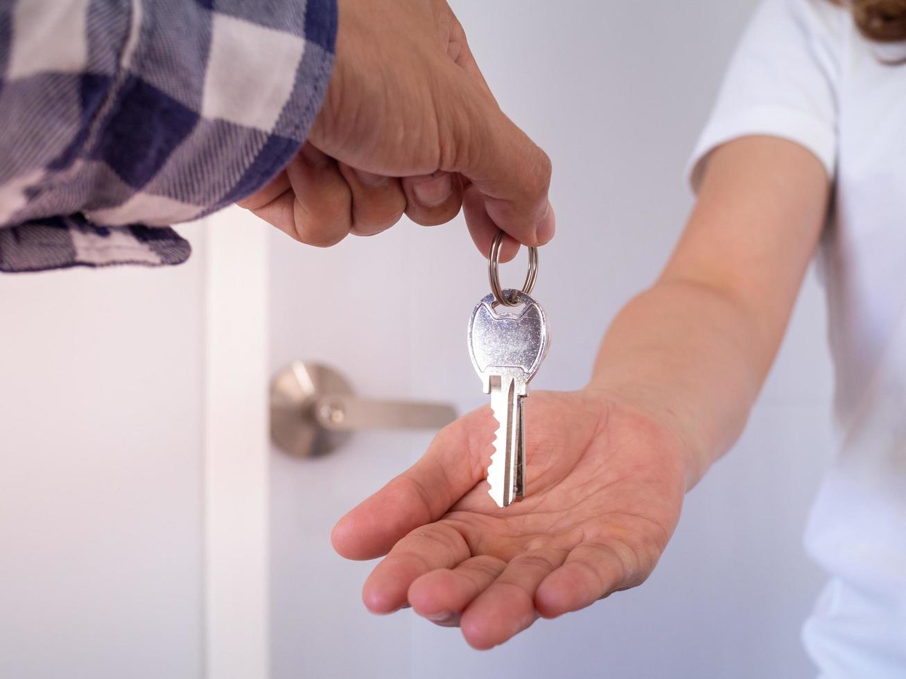 Das Mädchen reichte eine Hand, um den Schlüssel vom Hausverkäufer entgegenzunehmen. Wohnung zum Mietkauf nach Vertragsabschluss. foto