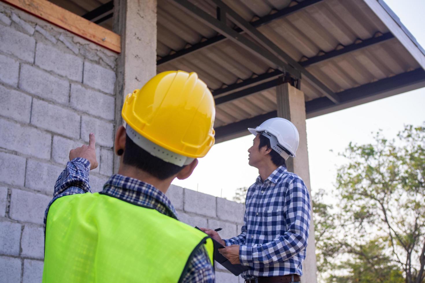 Die Inspektoren untersuchen die Struktur des Hauses und notieren sie in der Zwischenablage, um die Ingenieure darüber zu informieren, dass sie vor dem Verkauf an Kunden repariert werden müssen. foto