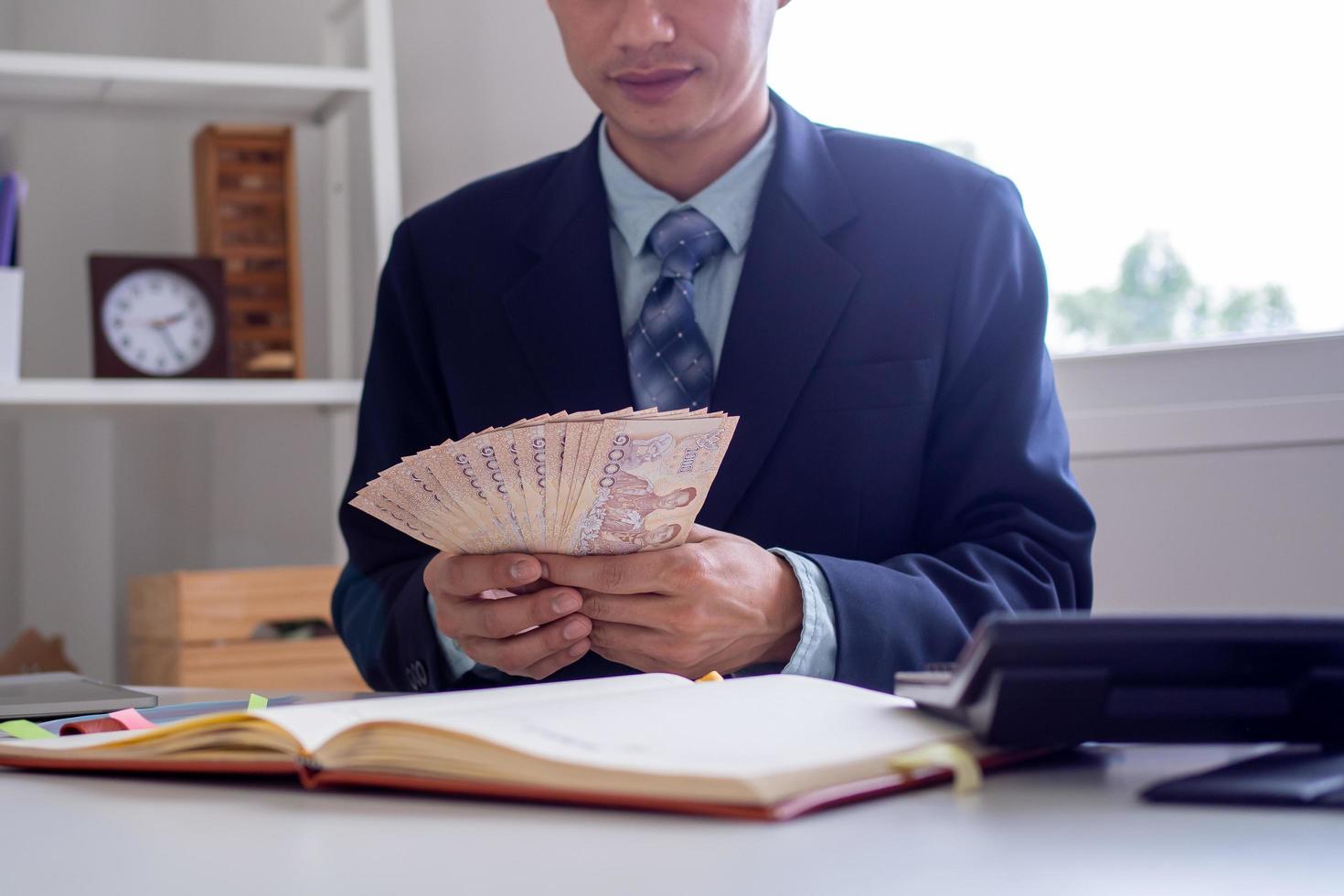 geschäftsleute sitzen und zählen geld thai baht auf dem schreibtisch im büro, die rentabilität von investitionen sinkt je nach wirtschaftlichen bedingungen foto