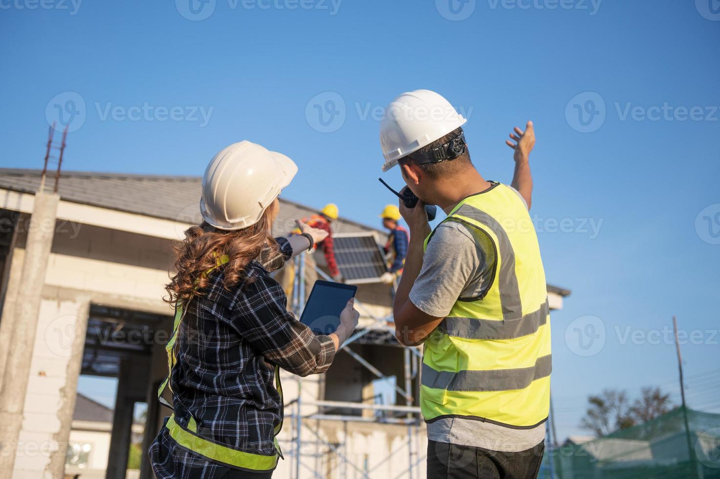 bauinspektor und architektin diskutieren mit chefingenieur asien über die installation von sonnenkollektoren bei einem bauprojekt. Besuchen Sie die Baustelle, um Sonnenkollektoren zu installieren. foto