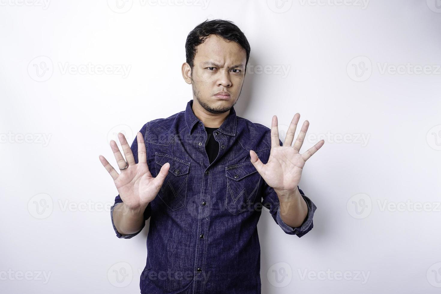 gut aussehender asiatischer mann, der blaues hemd mit handgestenhaltung des stopps oder des verbots mit kopienraum trägt foto