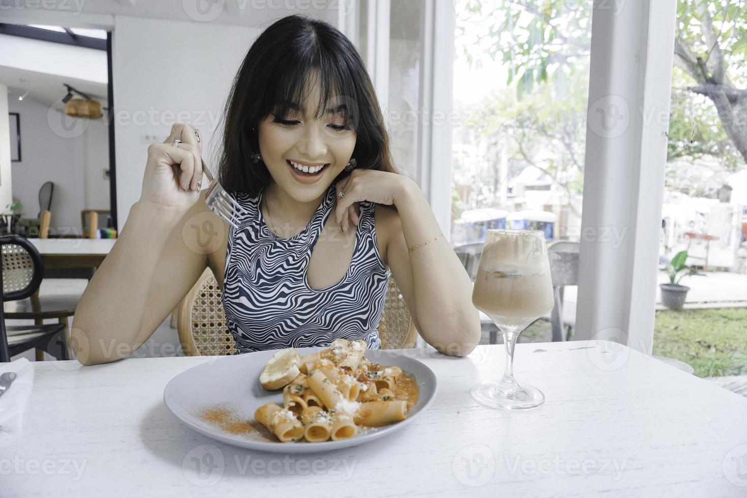 lustige junge asiatin, die leckere pasta im café isst foto