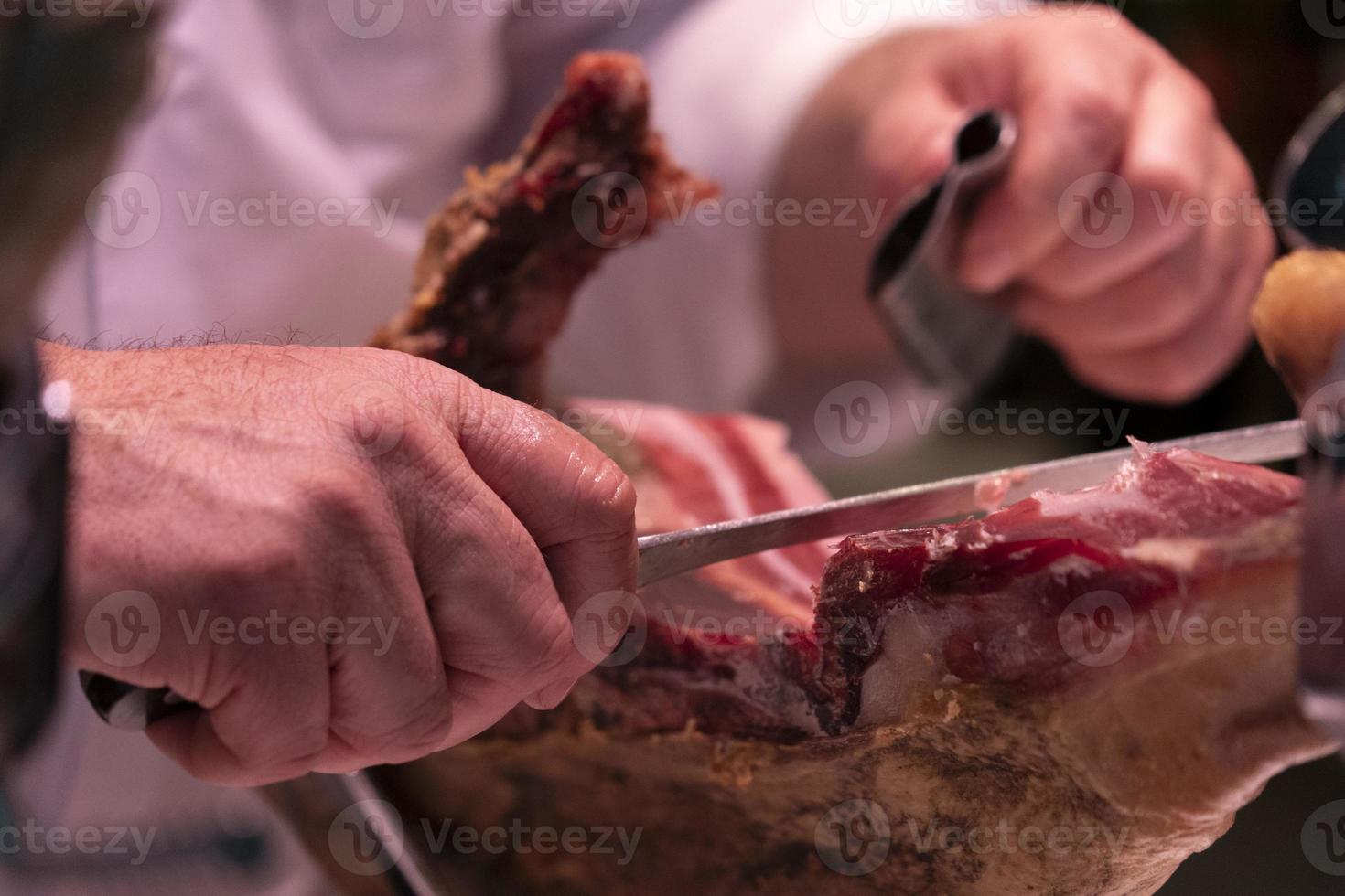 Hände beim Schneiden von spanischem Schinken foto