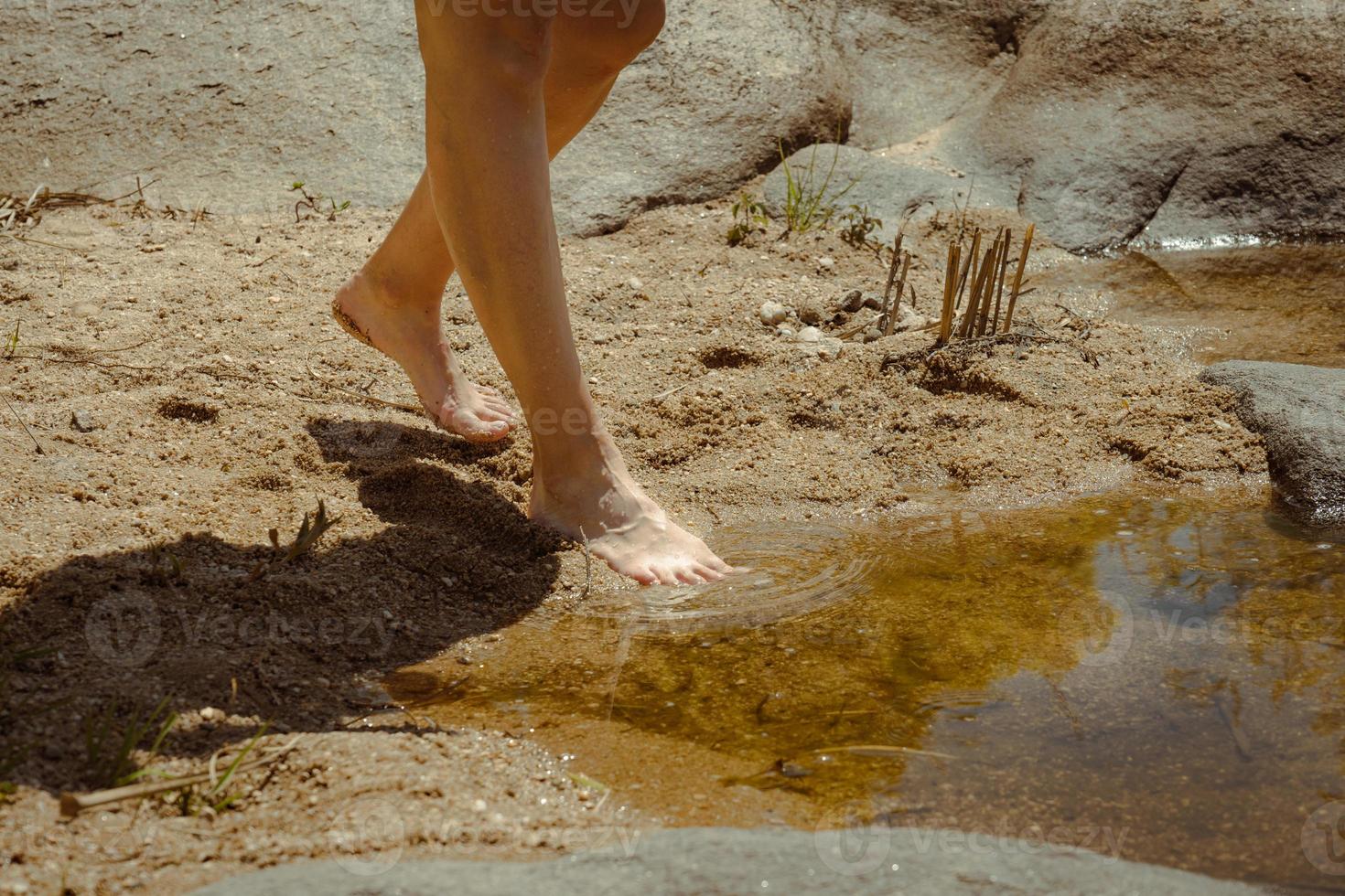 Die Füße der Frau entspannen sich im Sand und im Wasser des Flusses. foto