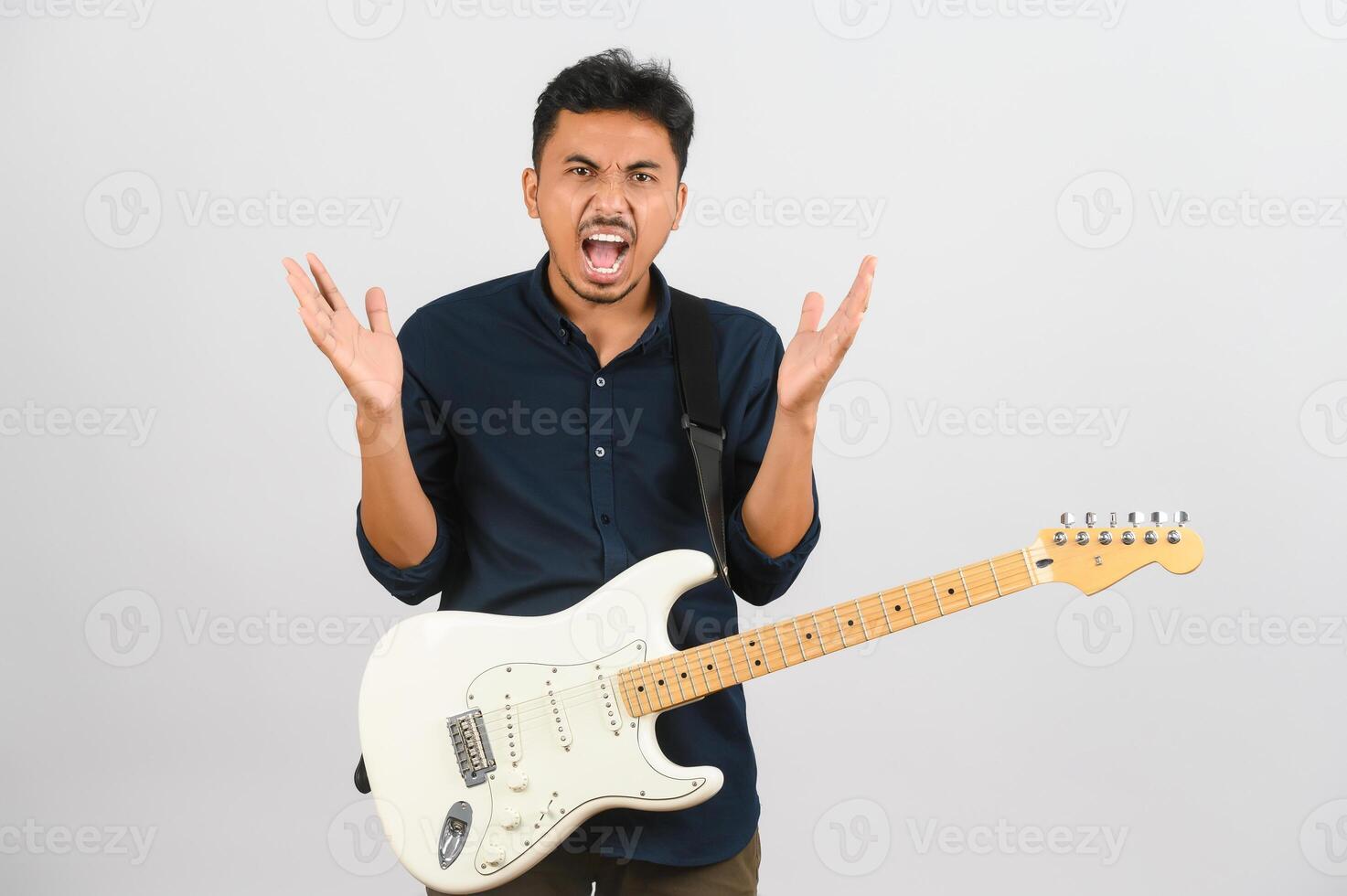 Porträt des jungen asiatischen Mannes im blauen Hemd mit E-Gitarre isoliert auf weißem Hintergrund foto