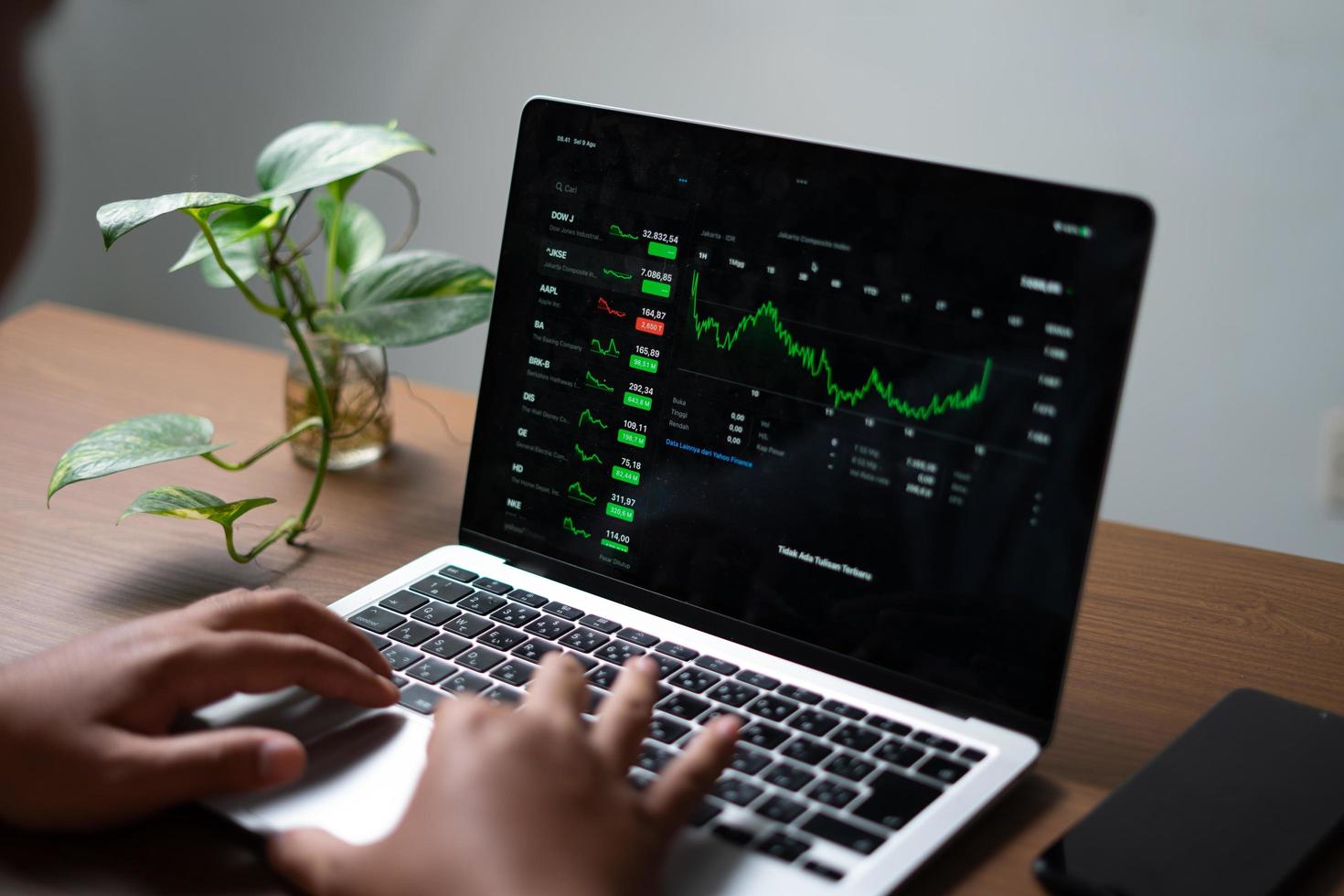 surabaya, indonesien 09 28 2022. geschäftsmann, der einen laptop-bildschirm mit einem diagramm steigender börsen betrachtet foto