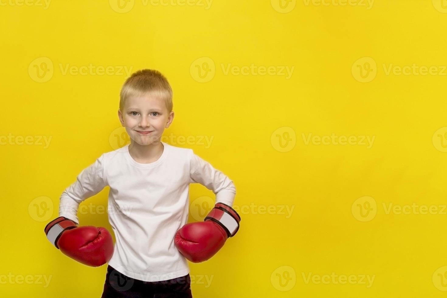 Junge in roten Boxhandschuhen auf gelbem Hintergrund mit Kopierraum foto