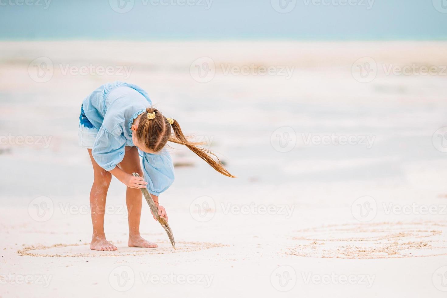 Entzückendes aktives kleines Mädchen am Strand während der Sommerferien foto