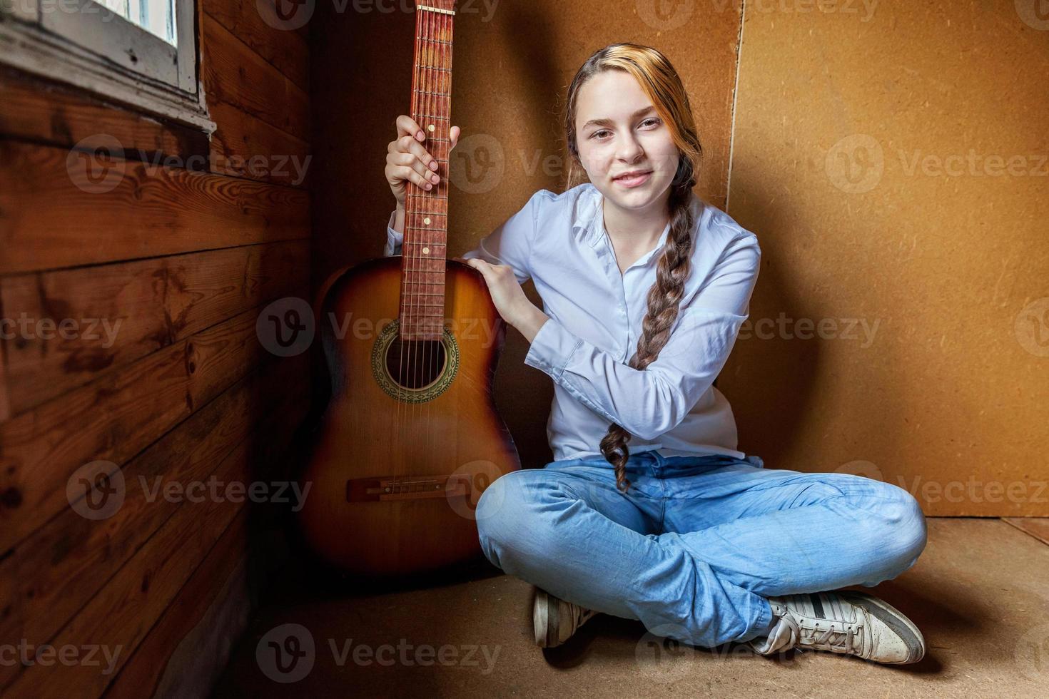 Junge Hipster-Frau, die auf dem Boden sitzt und zu Hause Gitarre spielt. Teenager-Mädchen lernen, Lieder zu spielen und Musik in ihrem Zimmer zu schreiben. hobby, lebensstil, entspannen, instrument, freizeit, bildungskonzept. foto