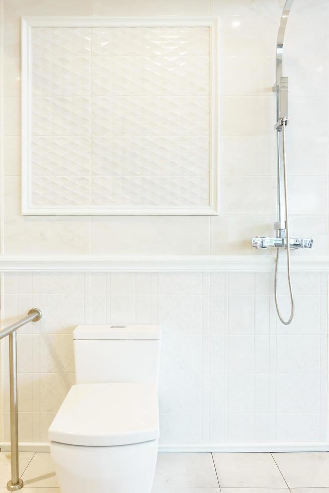 Badezimmerinnenraum mit Dusche, Wasserkocher und Toilette auf weißer Fliesenwand foto