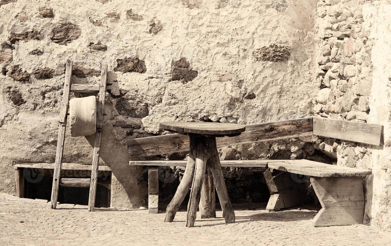 antiker Tisch und Holzbank vor einem Eckhaus foto