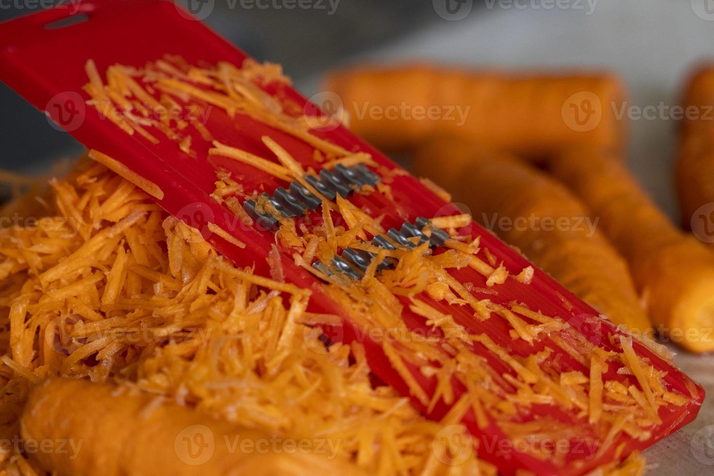 Reiben von Karotten auf einer Reibe für koreanische Karotten, Lebensstil, Kochen, gesunde Ernährung foto