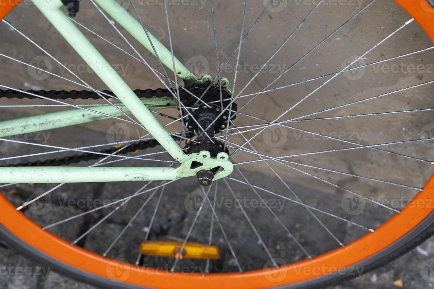 das Rad eines Stadtfahrrads, das an der Wand eines Cafés in der Stadt geparkt ist und mit dem Fahrrad zur Arbeit fährt foto