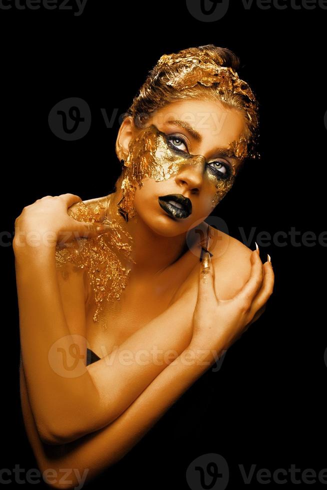 Modekunst goldene Haut. mädchenmodell mit festlichem goldenem glamour brillantem professionellem make-up. kreatives Make-up mit goldener Folie. foto