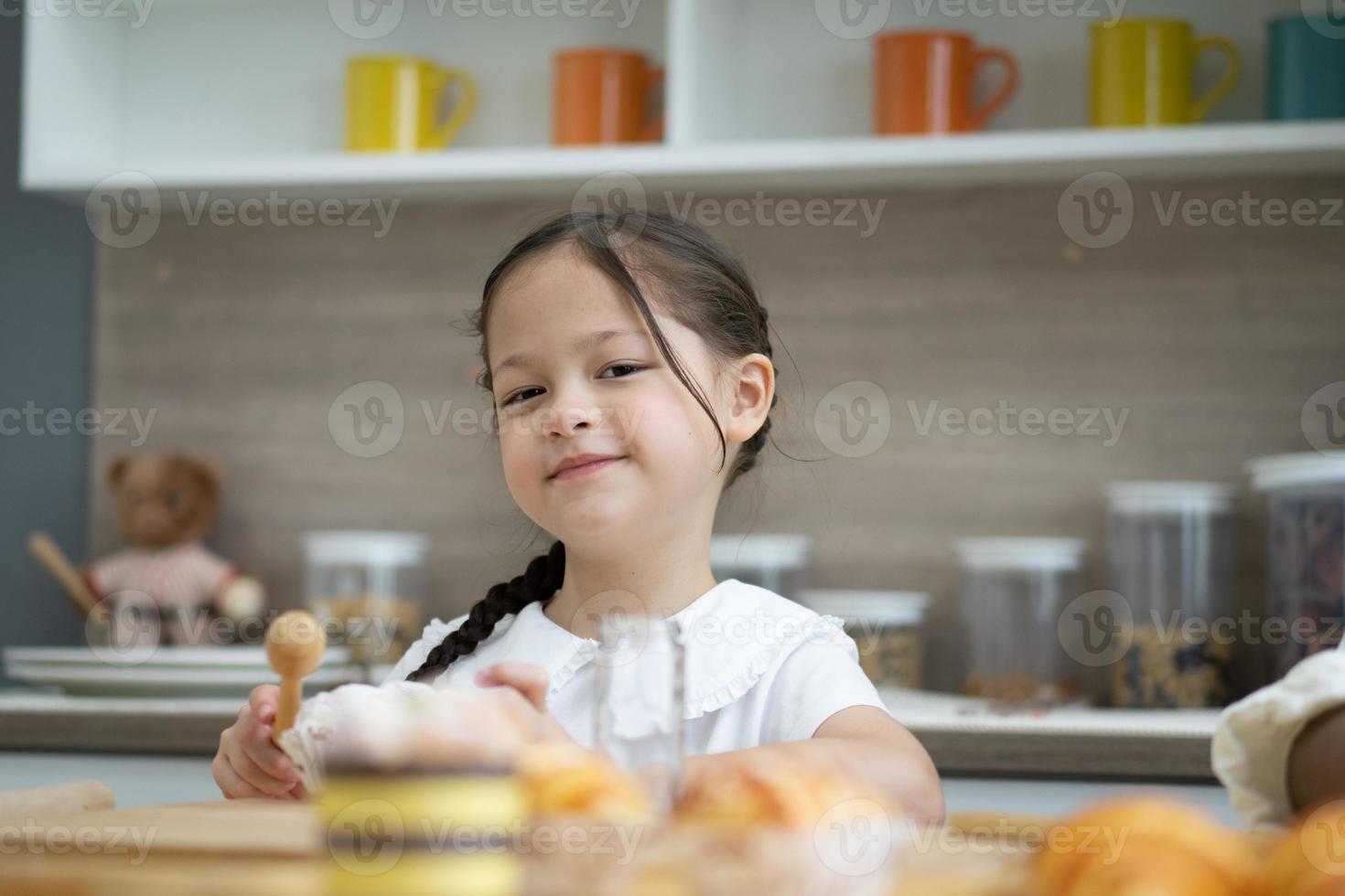 glückliche kleine kinder, die zusammen kochen, an der holzarbeitsplatte in der modernen küche stehen und hausgemachtes zubereiten foto