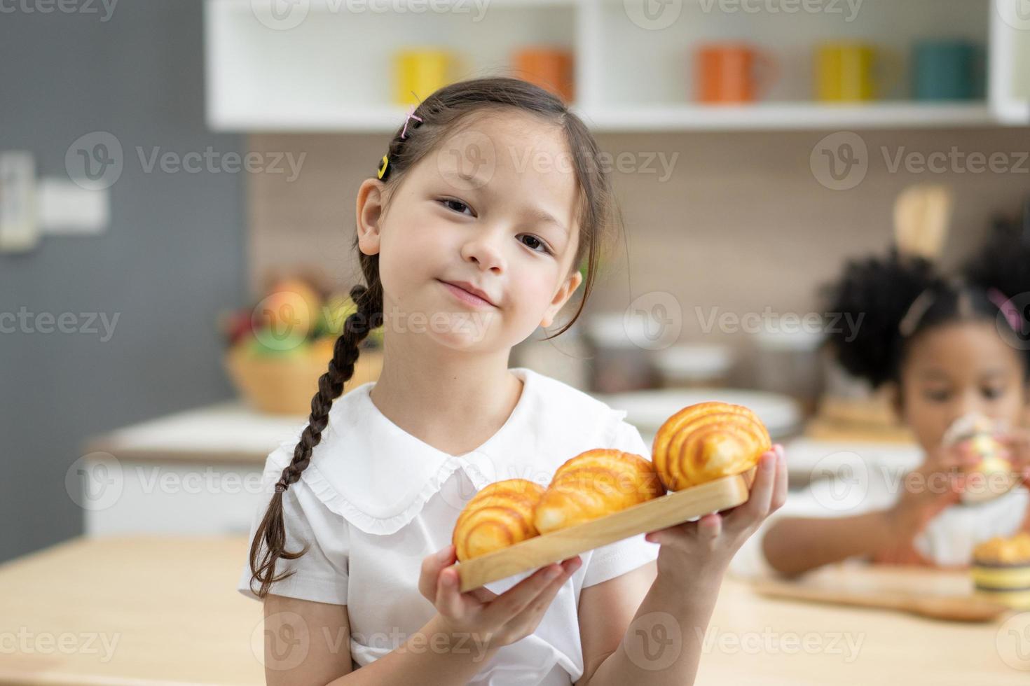 glückliche kleine kinder, die zusammen kochen, an der holzarbeitsplatte in der modernen küche stehen und hausgemachtes zubereiten foto