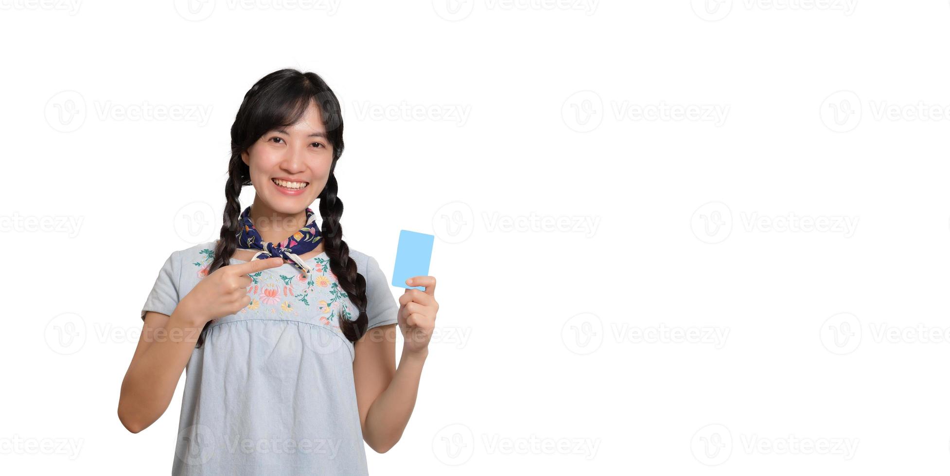 Portrait der schönen glücklichen jungen asiatischen Frau im Denimkleid, das Kreditkarte auf weißem Hintergrund hält foto