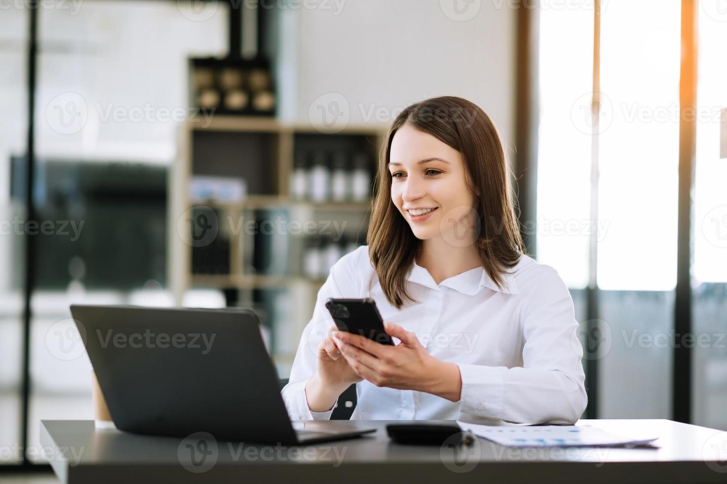 Selbstbewusste asiatische Frau mit einem Lächeln, das Notizblock und Tablet im modernen Büro hält. foto