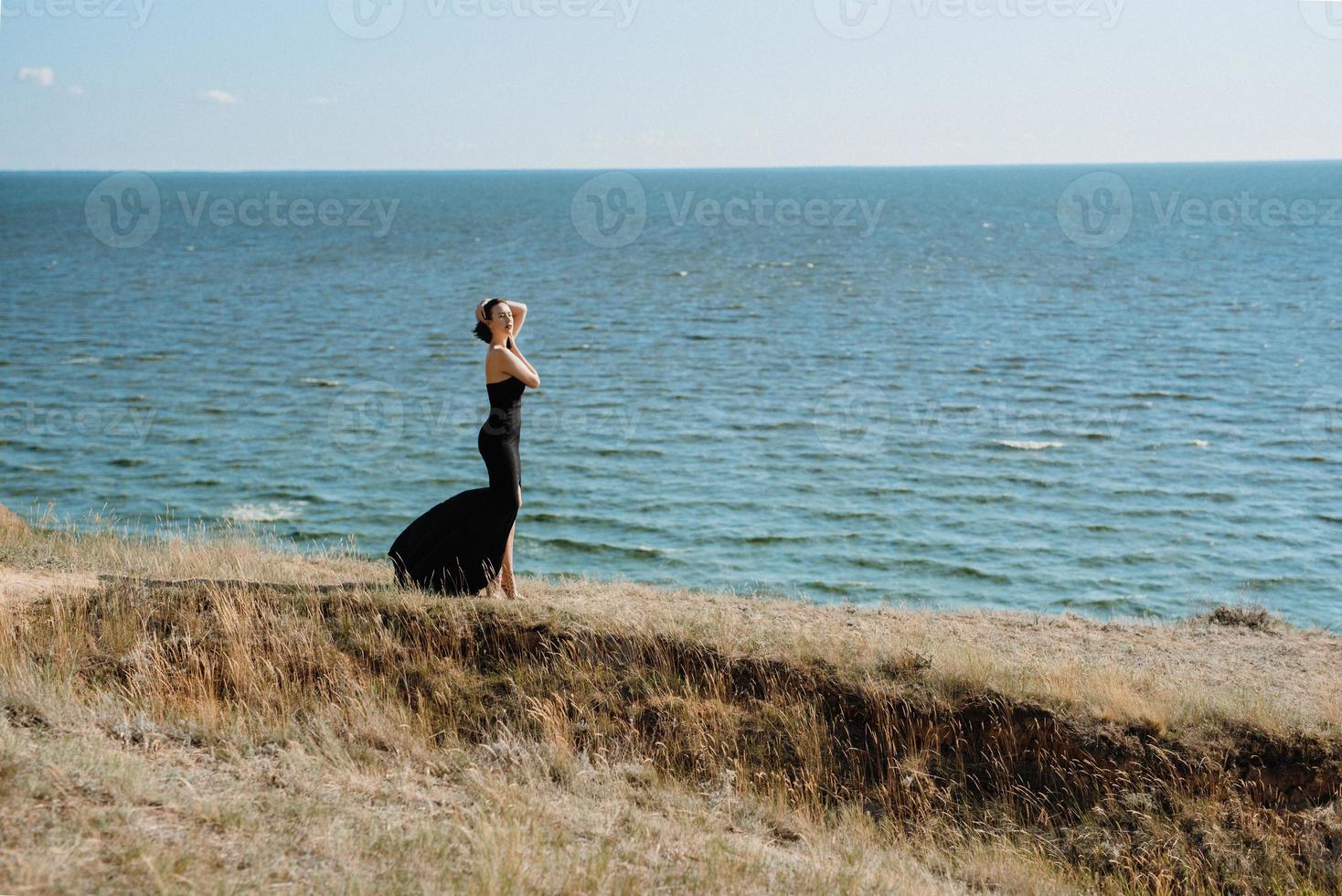 großes Mädchenmodell in einem schwarzen Kleid auf den Berghügeln foto