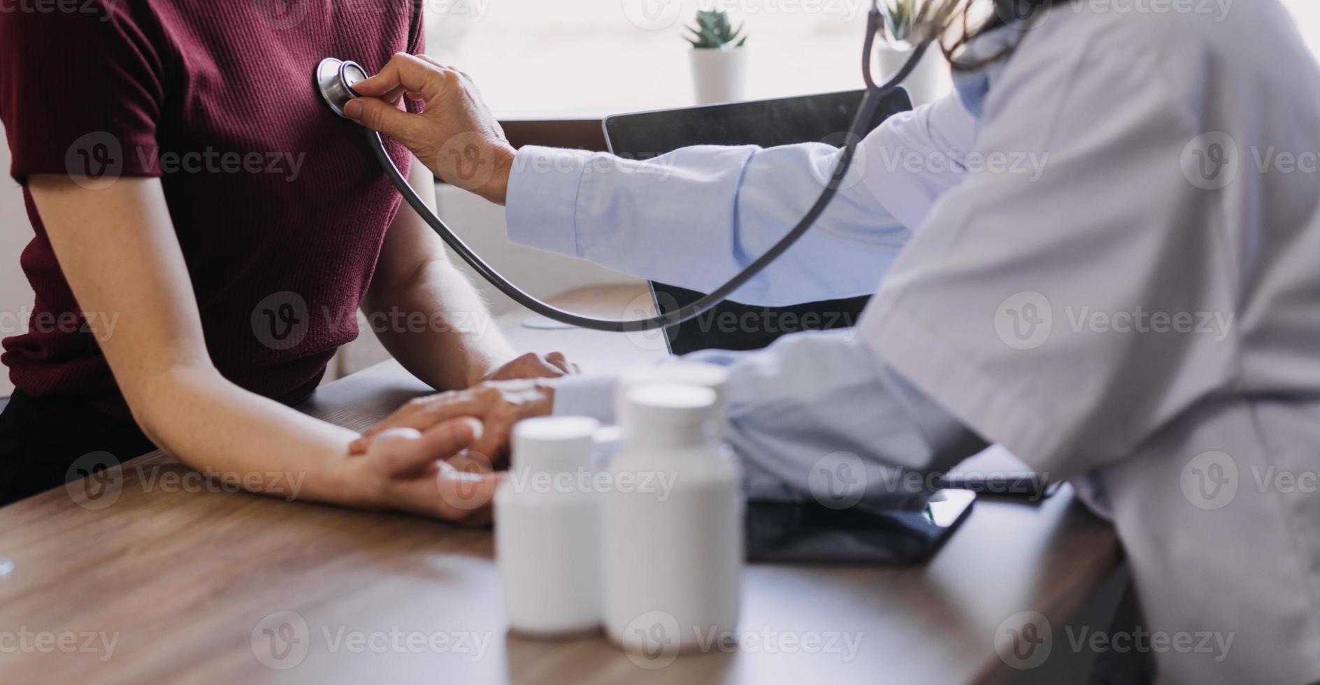 Homecare Pflegedienst und Kardiologie für ältere Menschen Gesundheitswesen. Nahaufnahme einer jungen hispanischen Ärztin, die während des Besuchs den Herzschlag eines reifen kaukasischen Mannes mit einem Stethoskop überprüft foto