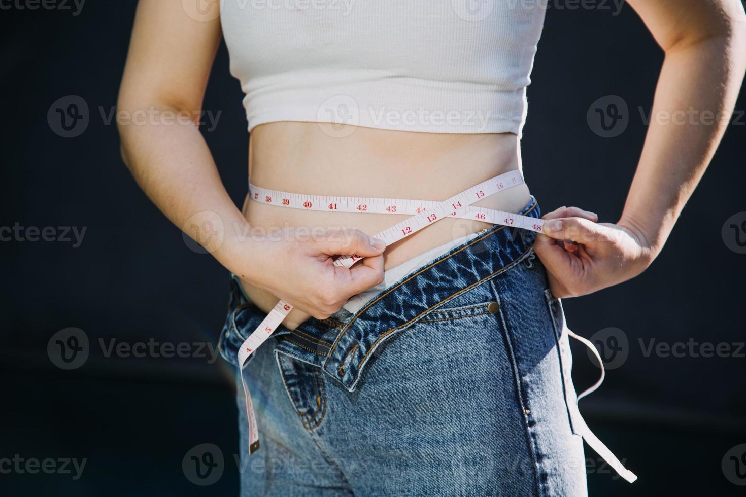 Fette Frau, dicker Bauch, mollige, fettleibige Frauenhand, die übermäßiges Bauchfett mit Maßband hält, Frauendiät-Lifestyle-Konzept foto