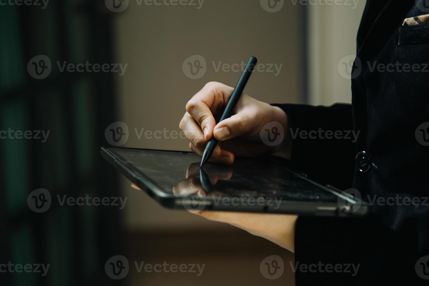 Reifer Geschäftsmann, der ein digitales Tablet verwendet, um Informationen mit einem jüngeren Kollegen in einer modernen Business-Lounge zu besprechen foto