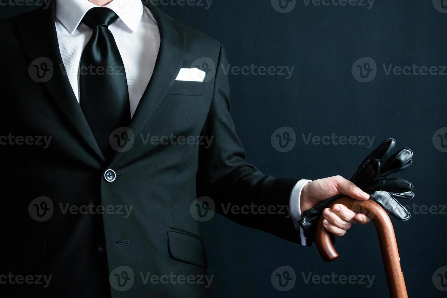 Porträt eines Herrn im schwarzen Anzug mit Lederhandschuhen und Regenschirm. foto