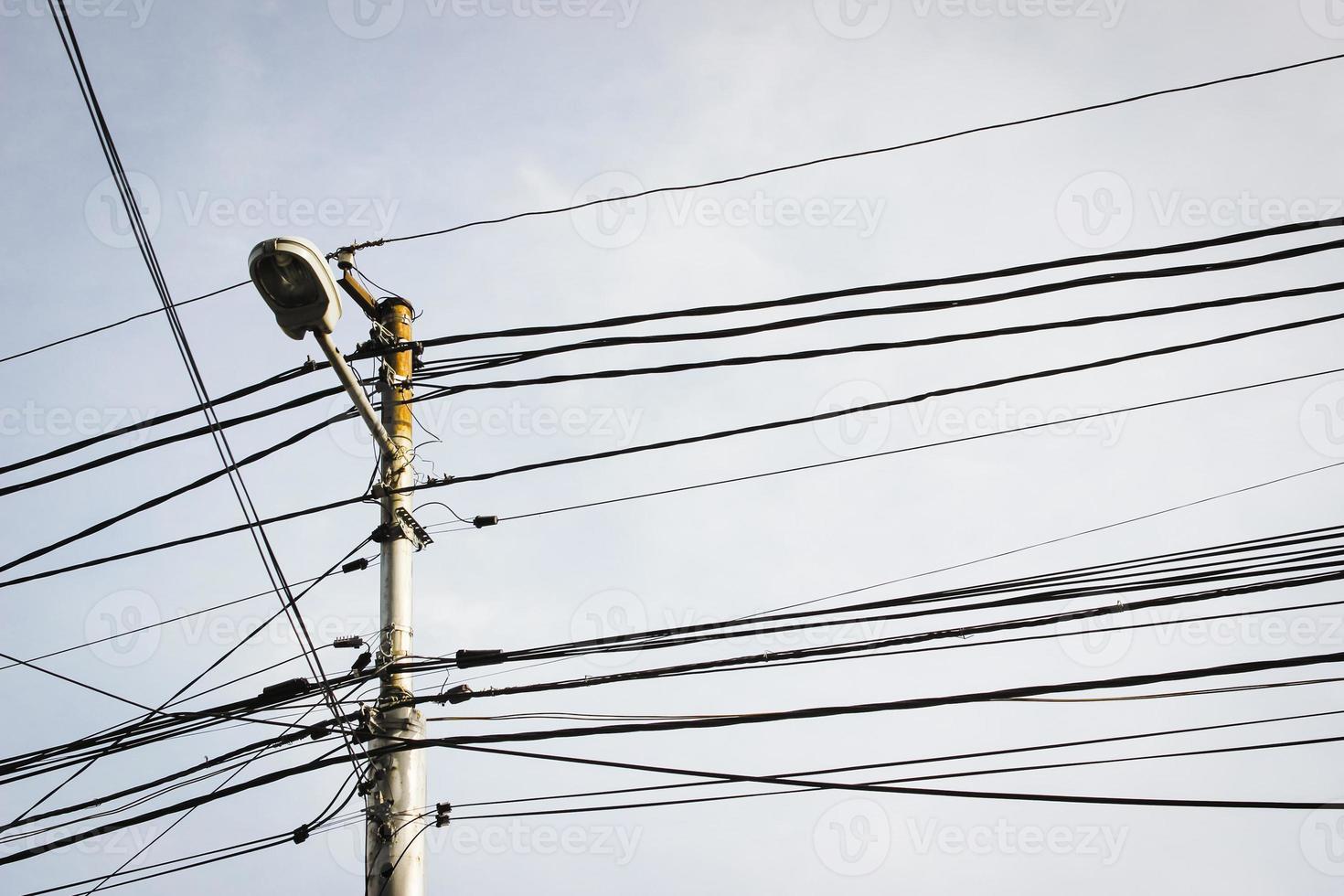 Strommast mit Straßenlaterne und vielen Kabeln. foto