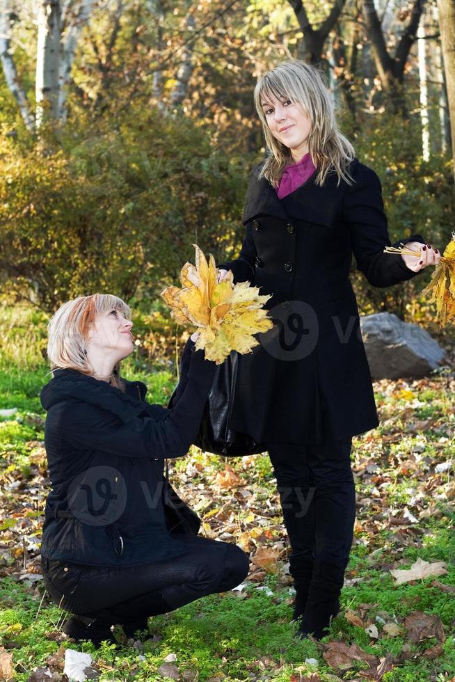 Zwei schöne junge Frauen mit Herbstlaub im Park foto