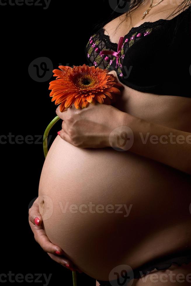 Bauch einer schwangeren Frau mit Blume. isoliert foto